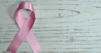 A pink breast cancer ribbon laying on a wooden table