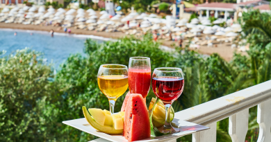 A selection of colorful fruits and drinks sitting on a platter overlooking a beach resort.