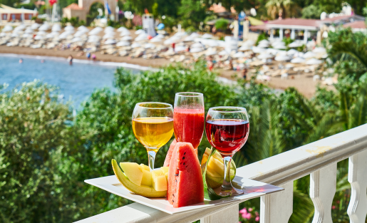 A selection of colorful fruits and drinks sitting on a platter overlooking a beach resort.