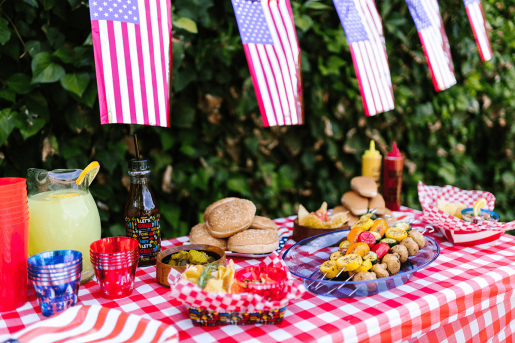 An outdoor picnic spread with burgers, hot dogs and healthy vegetable kebabs.