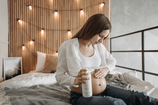 A pregnant person rubbing a skin product into their stomach.