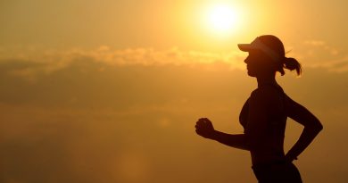 A person jogging at sunset, their body a silhouette in front of an orange sky and sun