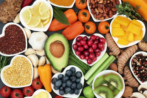 A spread of colorful fruits and vegetables, such as peppers, berries, avocado, nuts and kiwi.