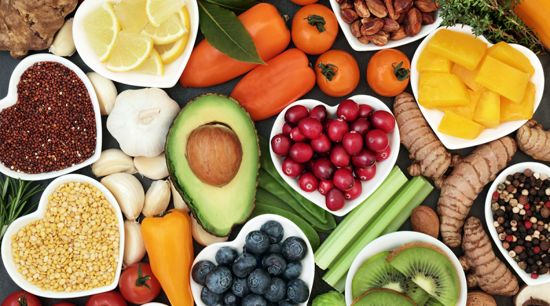 A spread of colorful fruits and vegetables, such as peppers, berries, avocado, nuts and kiwi.