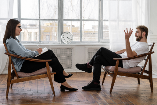 Two people seated facing each other during a therapy session.