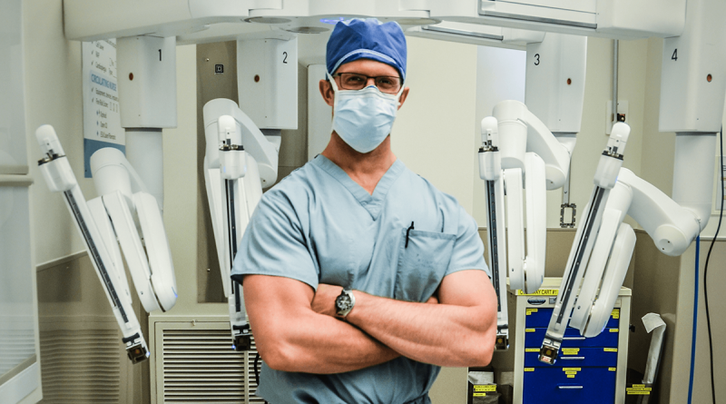 Dr. Shawn Groth stands in front of his robotic surgery device.