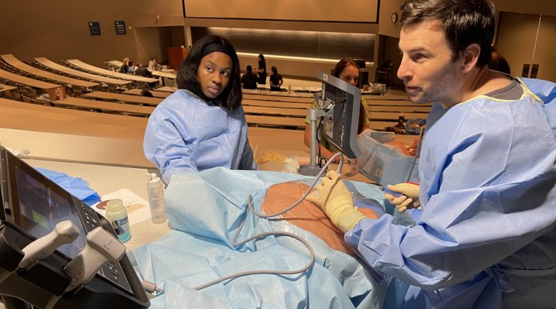 Two trainees working on a simulation mannequin inside a classroom.
