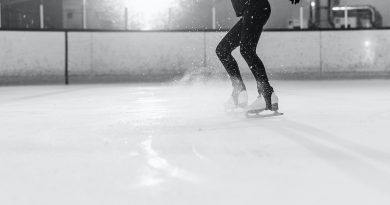 A person seen from the neck down about to jump into the air while ice skating