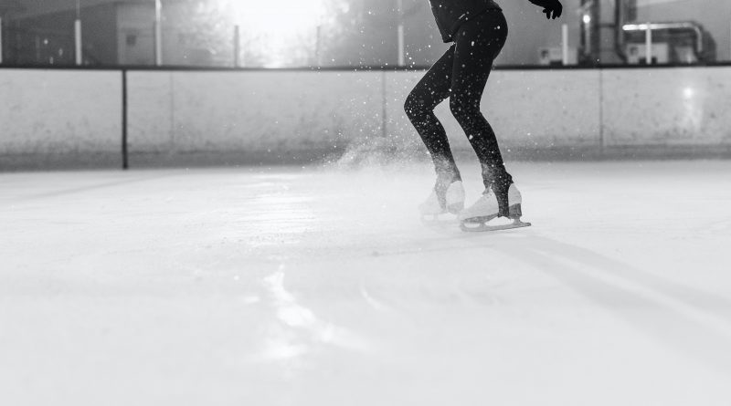 A person seen from the neck down about to jump into the air while ice skating