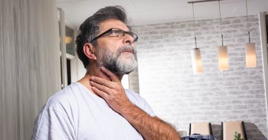 A person holding their neck and throat with a pained expression.