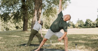 Two older adults doing yoga outside.