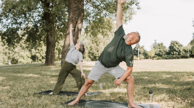 Two older adults doing yoga outside.