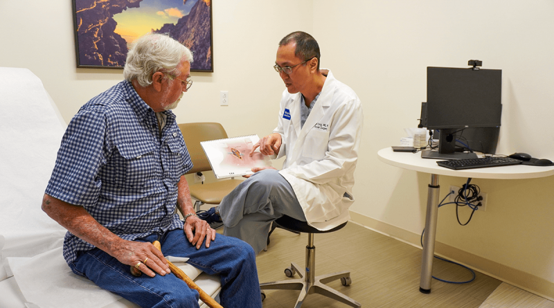 A doctor showing an older patient an illustration of inside the human neck.