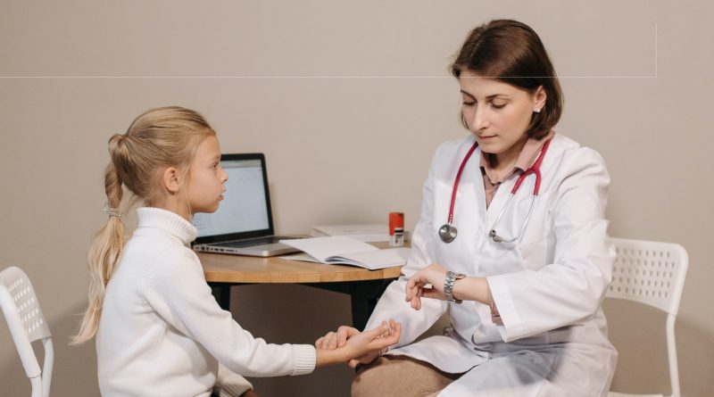 A doctor holding their hand to a child's wrist while checking their pulse.