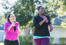Two people jogging outside while holding pink weights
