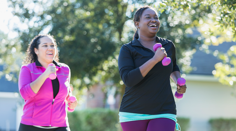 Two people jogging outside while holding pink weights