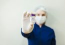 Person in face mask holds vial of Botox up for camera.