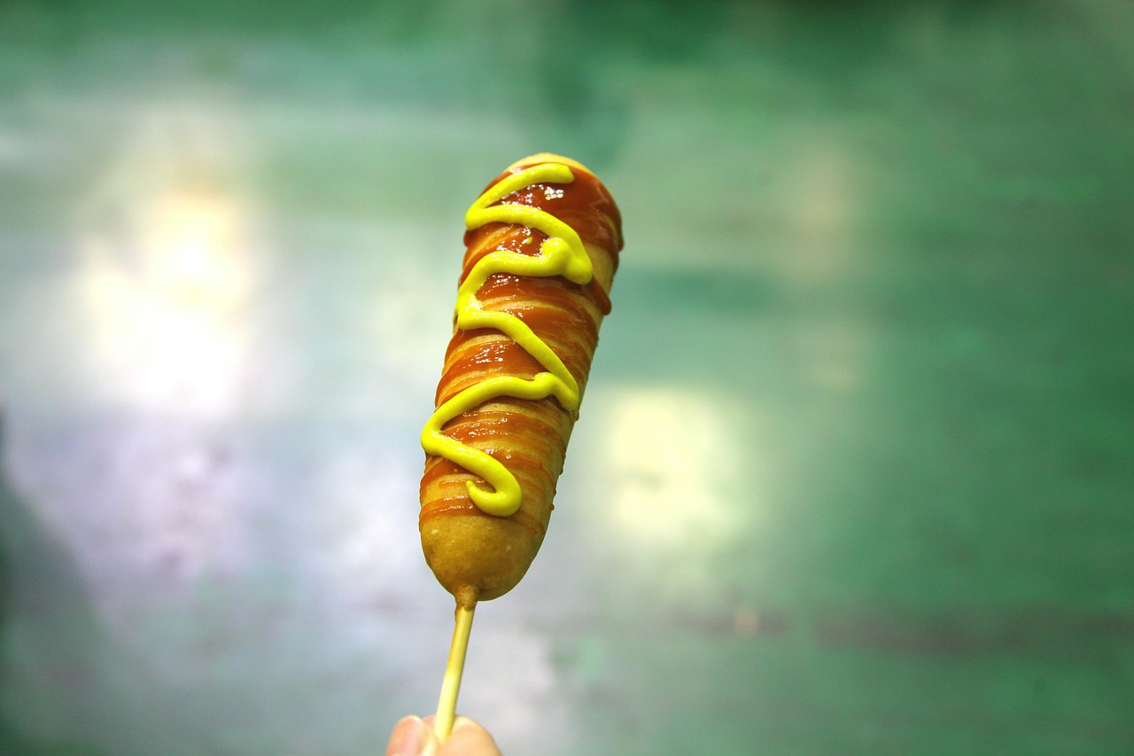 A corn dog drizzled with honey and mustard.
