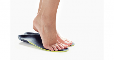 A pair of human feet from the ankle down, standing on top of a blue pad.