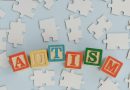 The word "autism" spelled out in building blocks, sitting among a group of puzzle pieces.
