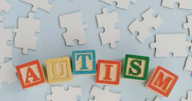 The word "autism" spelled out in building blocks, sitting among a group of puzzle pieces.