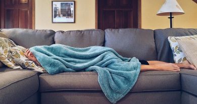 A person laying under a blanket on a couch.