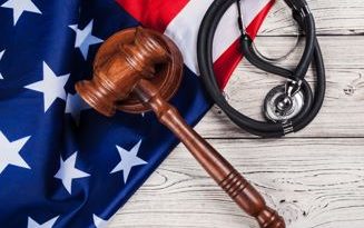 A United States flag with a judge's gavel and a stethoscope laying across it