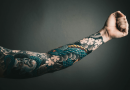 An arm extended to show a full sleeve of tattoos.