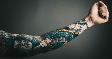 An arm extended to show a full sleeve of tattoos.