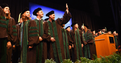 A group of graduating students in black and green robes.