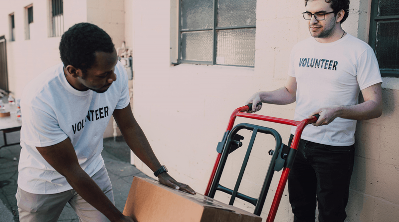 Two people wearing shirt reading Volunteer pack boxes onto a hand cart.