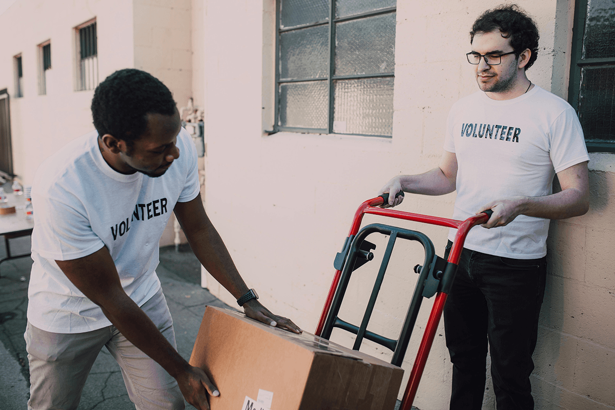 Two people wearing shirt reading Volunteer pack boxes onto a hand cart.
