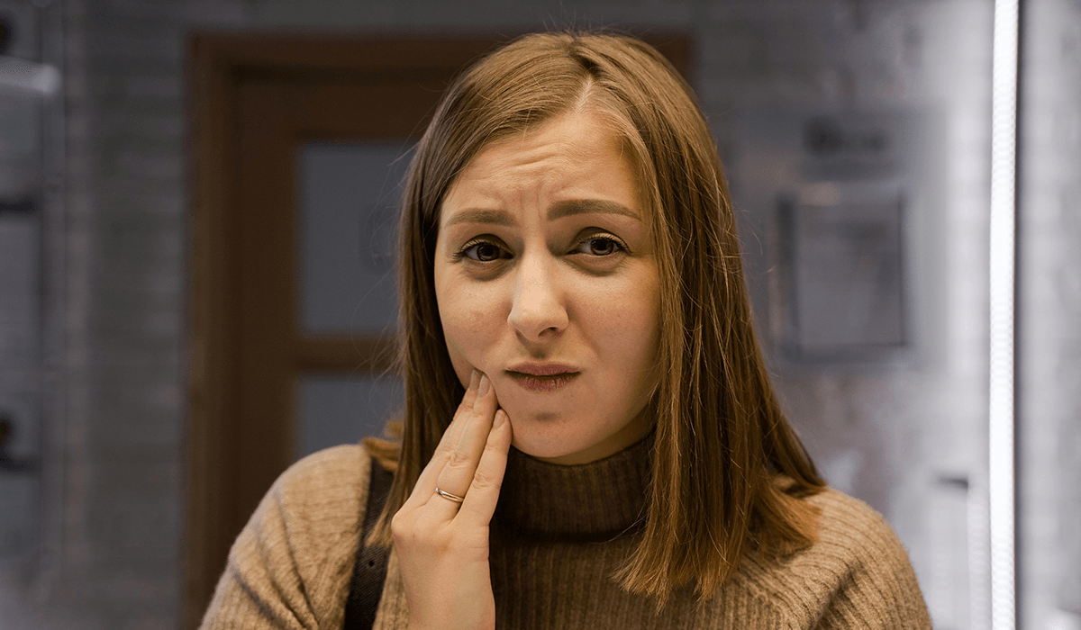 A person holding their cheek with a pained expression.