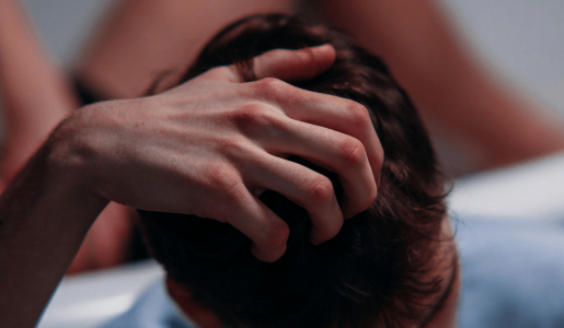 A person's hand scratching the hair on their head.