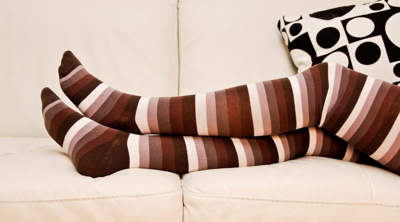 A person's legs clad in white and brown stripped stockings.