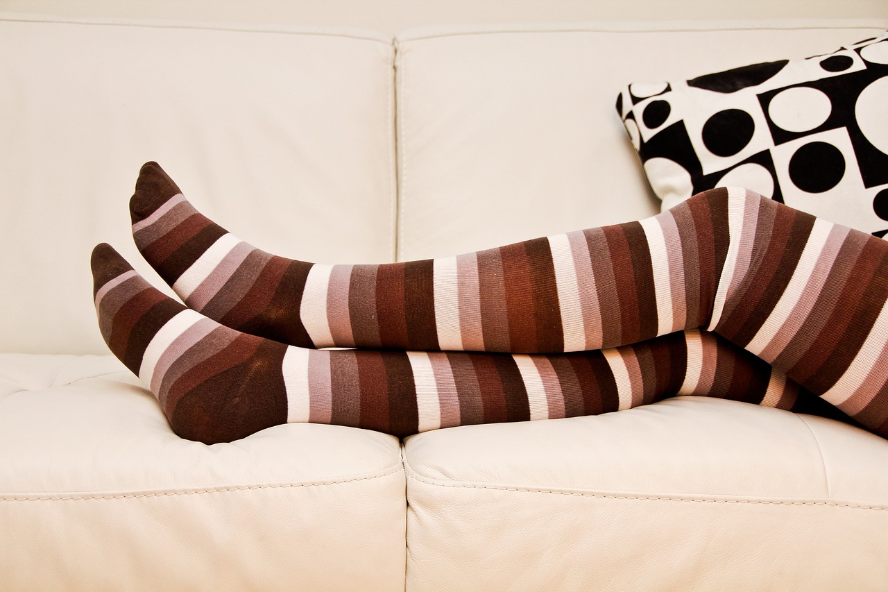 A person's legs clad in white and brown stripped stockings.