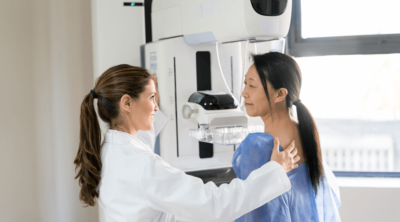 A doctor helping a patient prepare for a mammogram