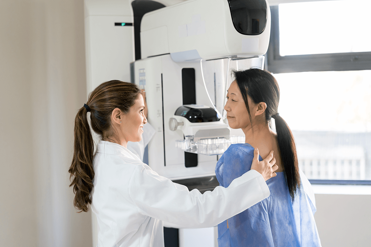 A doctor helping a patient prepare for a mammogram