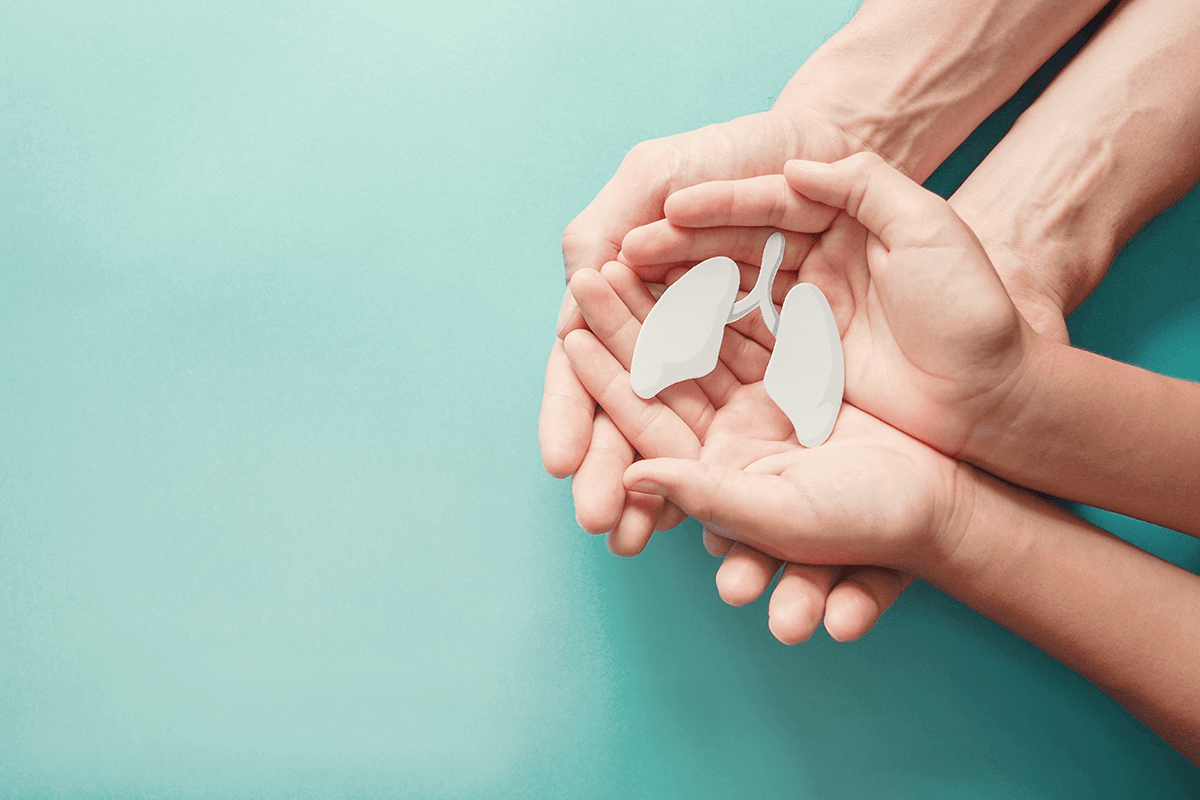 A set of hands holding a small paper cutout of lungs.