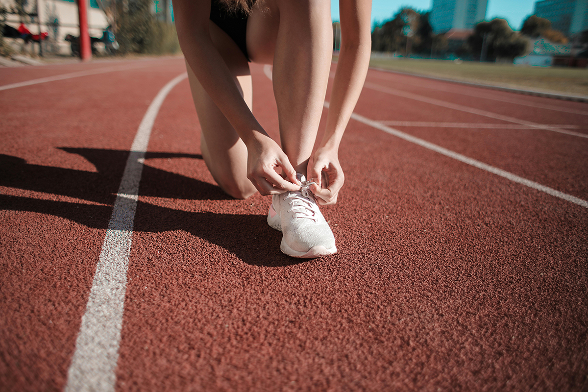 A person on a sprinting track tying their shoes