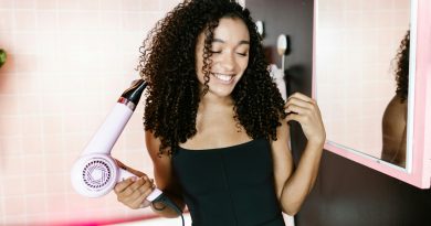 A person blow drying their long and curly hair.