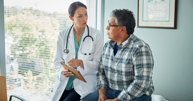 A doctor and patient discussing information on a chart while sitting together on an exam table.