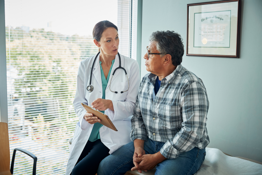 A doctor and patient discussing information on a chart while sitting together on an exam table.