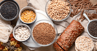 Several bowls of grains, pastas, corn, seeds and beans.