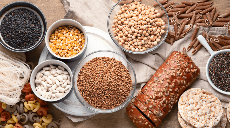 Several bowls of grains, pastas, corn, seeds and beans.