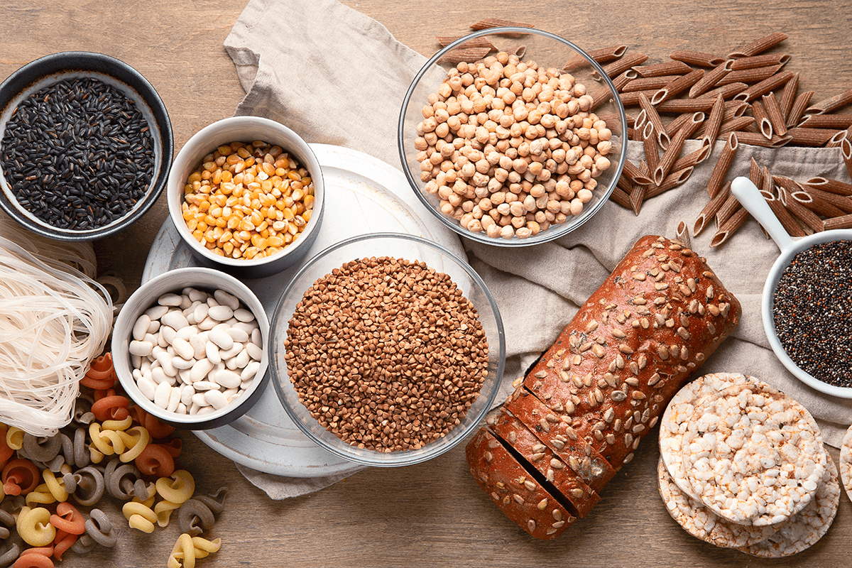 Several bowls of grains, pastas, corn, seeds and beans.