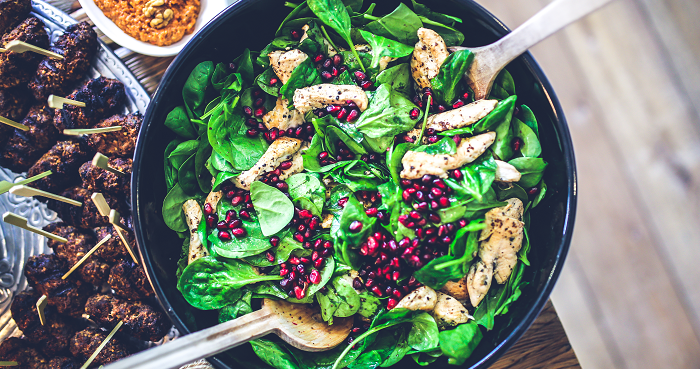 A healthy spinach salad with chicken and cranberries.