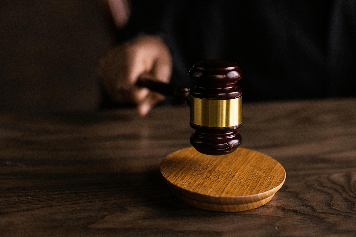 A hand bringing a gavel down onto a sound block.