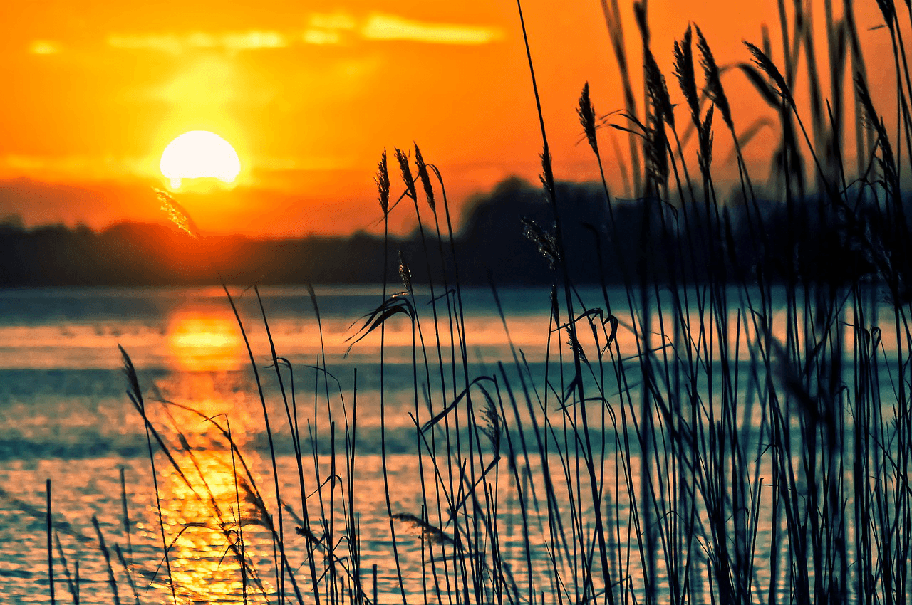 A lake with a bright orange sunset reflecting off it.