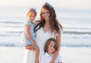 A smiling woman on a beach with two children.